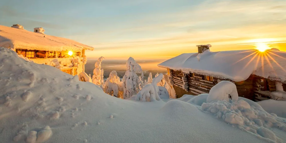 Sunrise over snowy cabins in Lapland